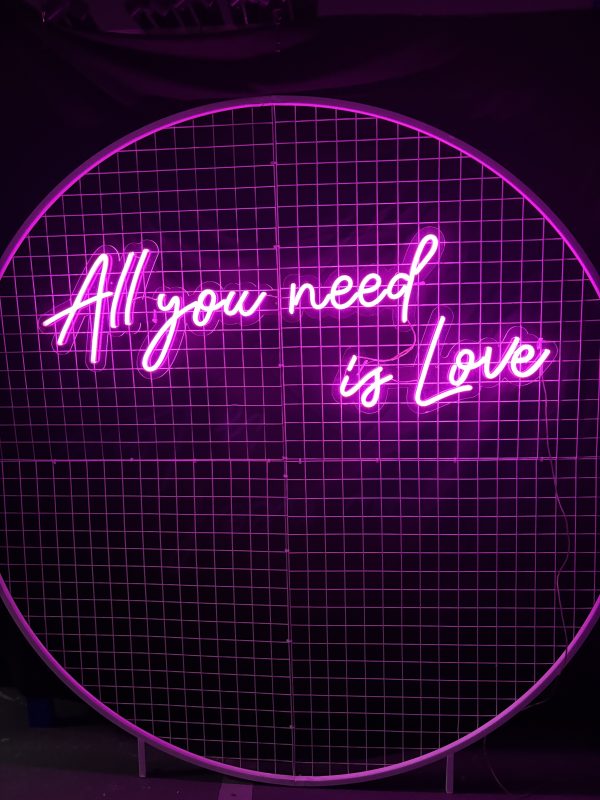 All you need is love neon sign on white round mesh backdrop