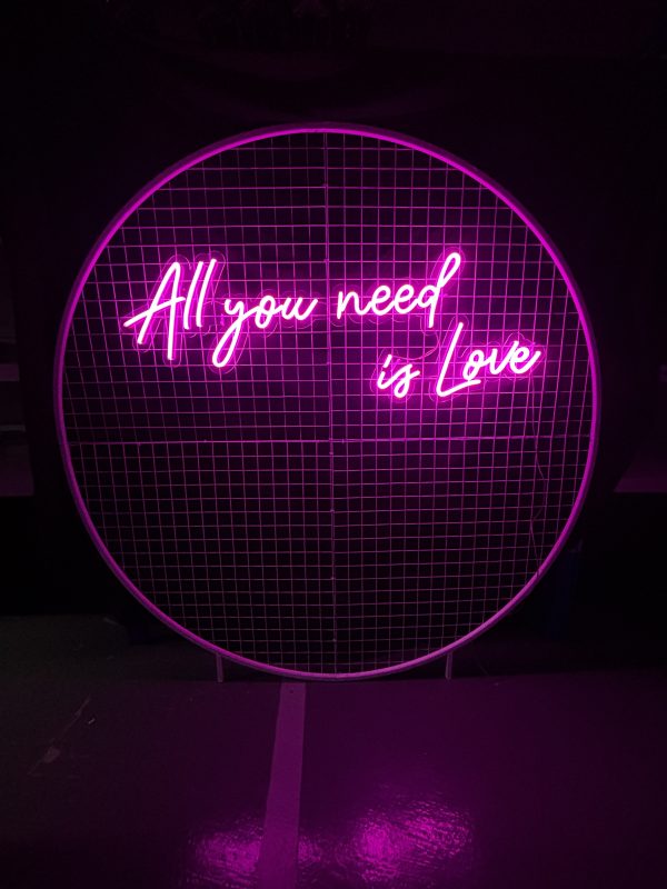 All you need is love neon sign on a white round mesh backdrop