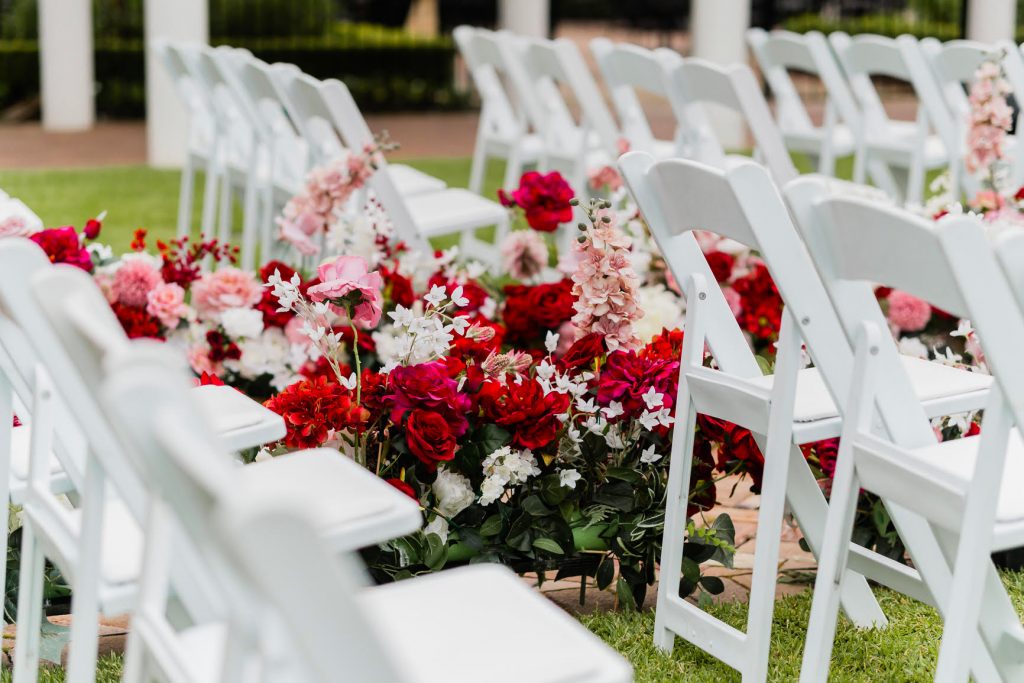 white folding chair at a wedding with red decorative flowers