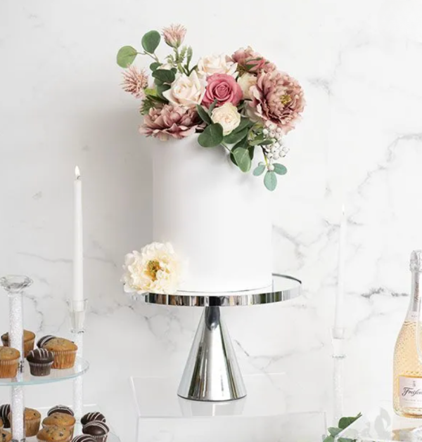 white one tier cake decorated with florals on a silver chrome cake stand